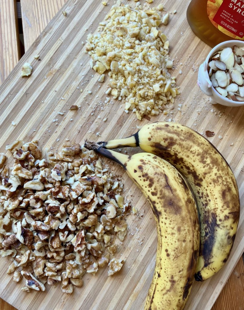 Ingredients on a cutting board-walnuts, bananas, banana chips, almonds and maple syrup