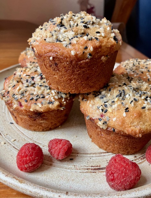 a stack of raspberry muffins with raspberries scattered on the plate