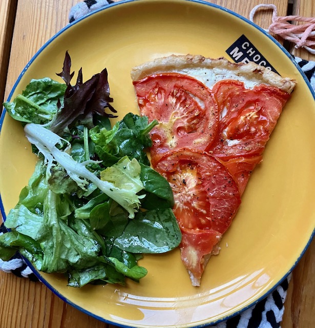 slice of tomato tart on a plate with a green salad