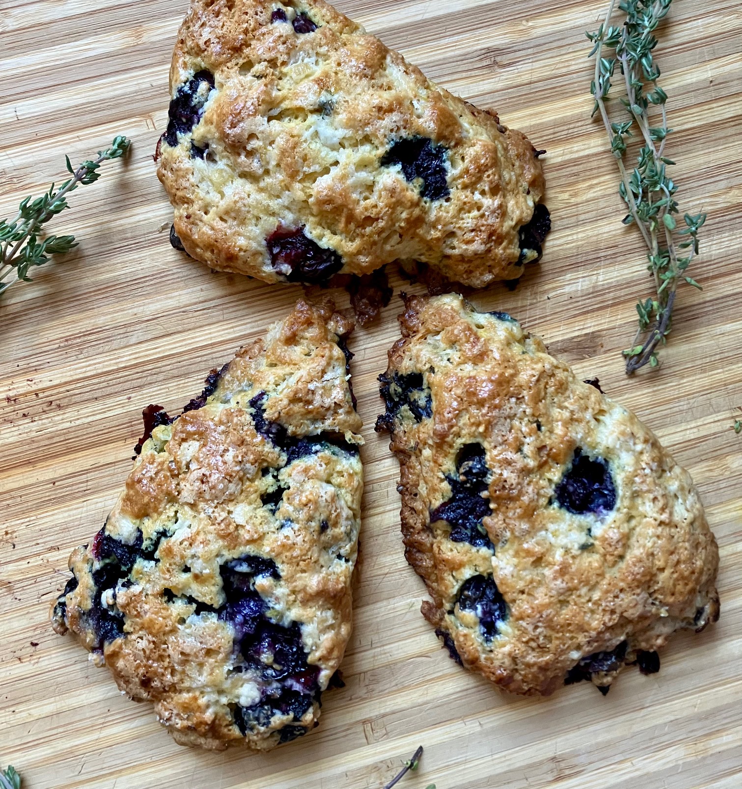 preserved lemon blueberry scones on a cutting board with sprigs of thyme