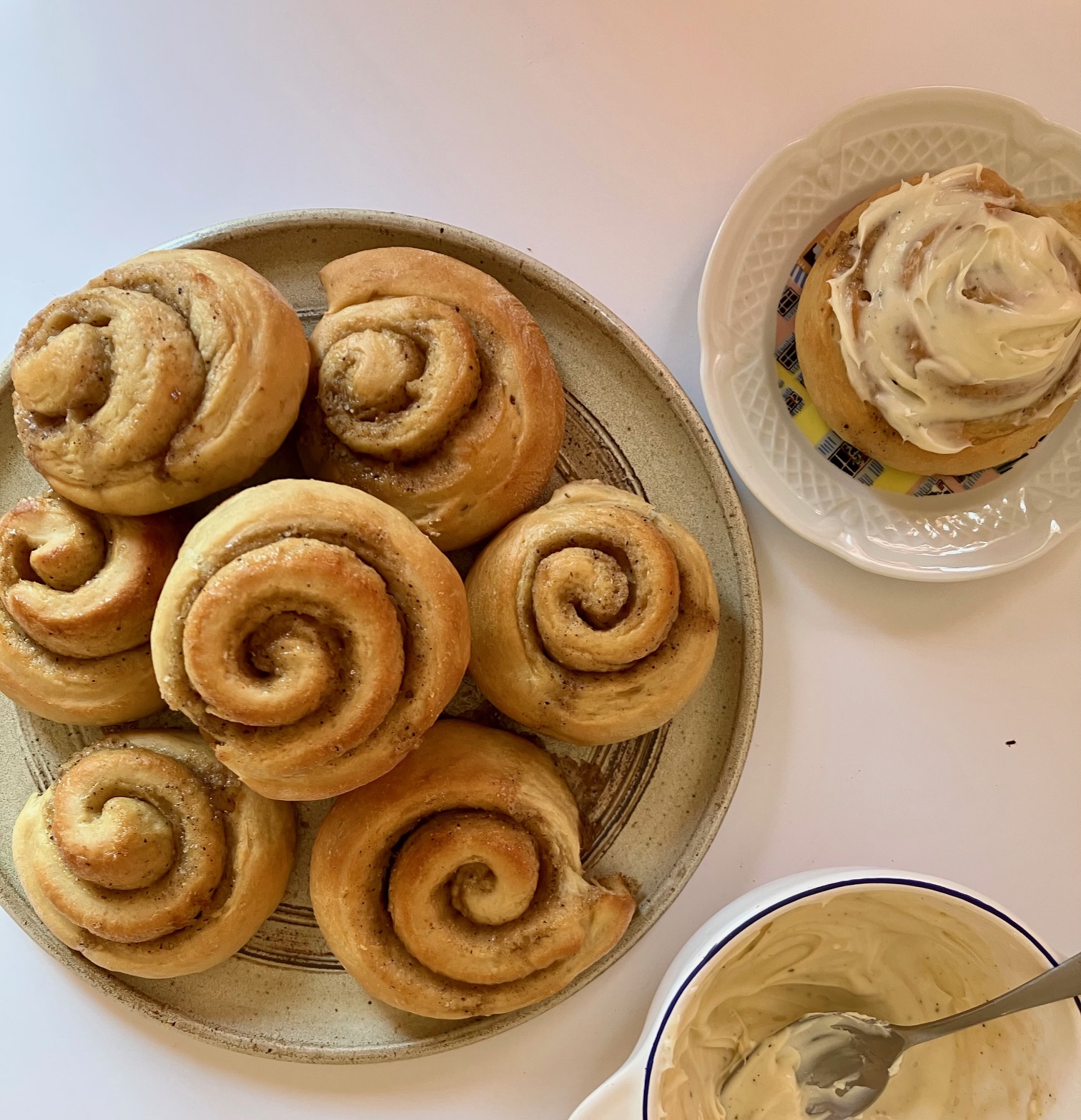 Masala chai cinnamon rolls piled on a plate, with an iced roll on the side