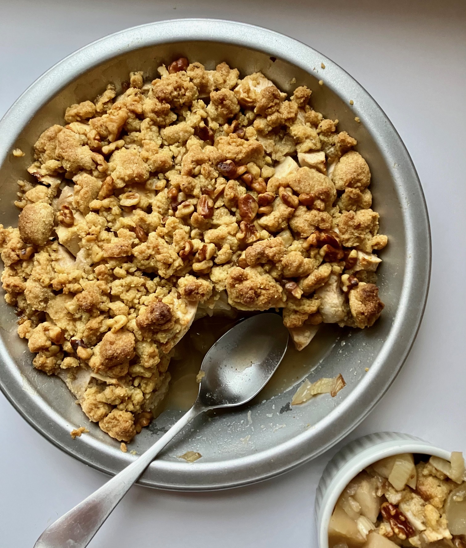 Caramelized apple fennel crisp in a pie plate next to a ramekin with a single serving