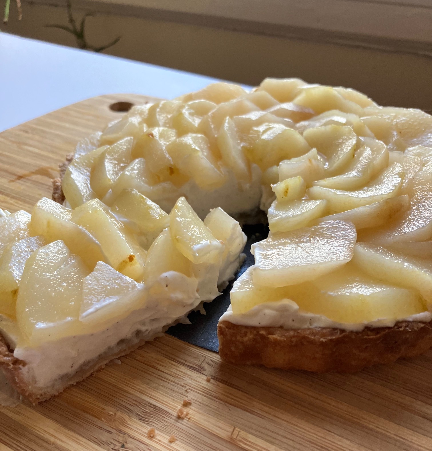 poached pear tart on a cutting board with one slice removed