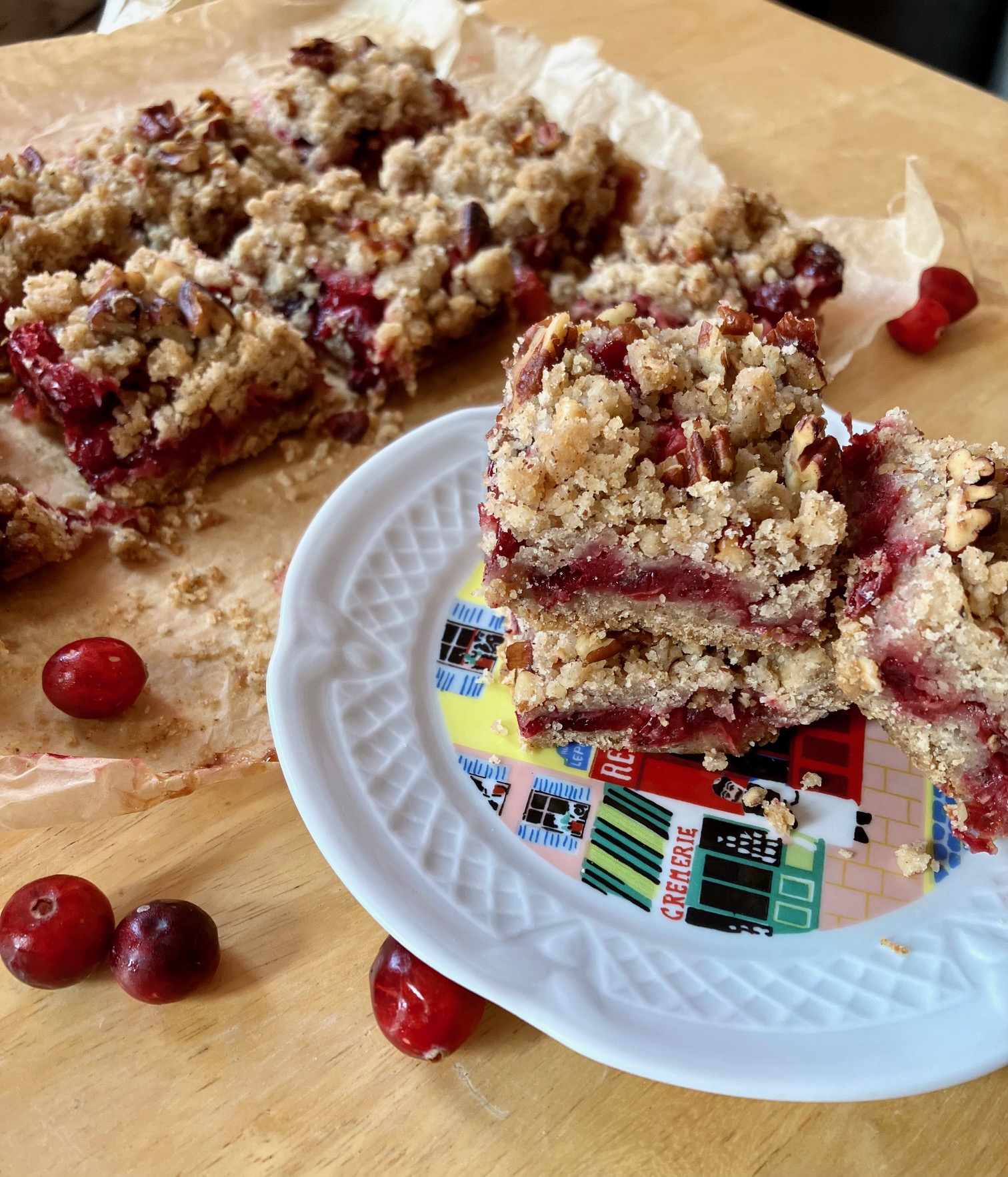 Cranberry crumb bars on parchment paper and stacked on a plate