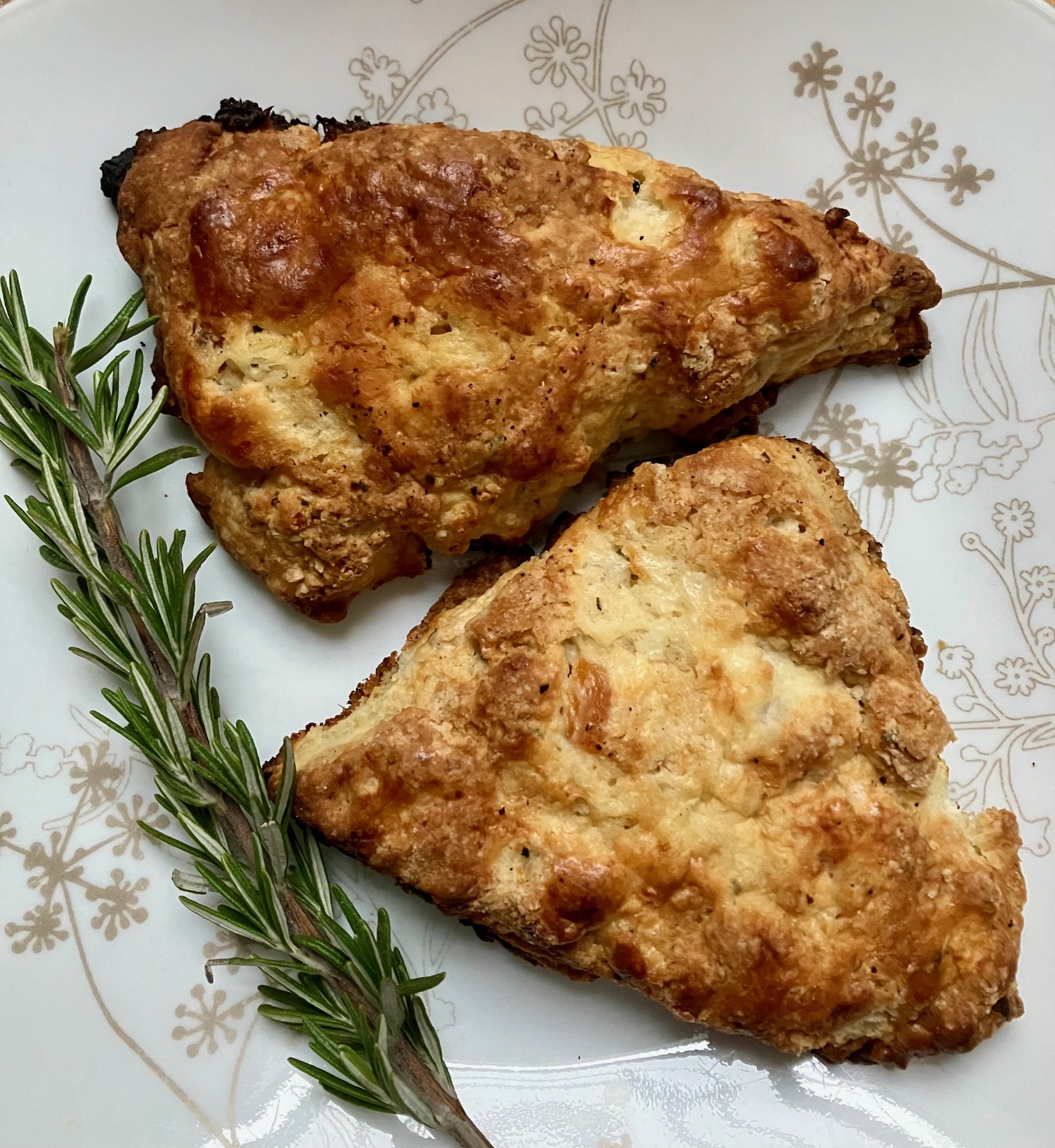 apricot scones with goat cheese and rosemary on a plate next to a sprig of rosemary