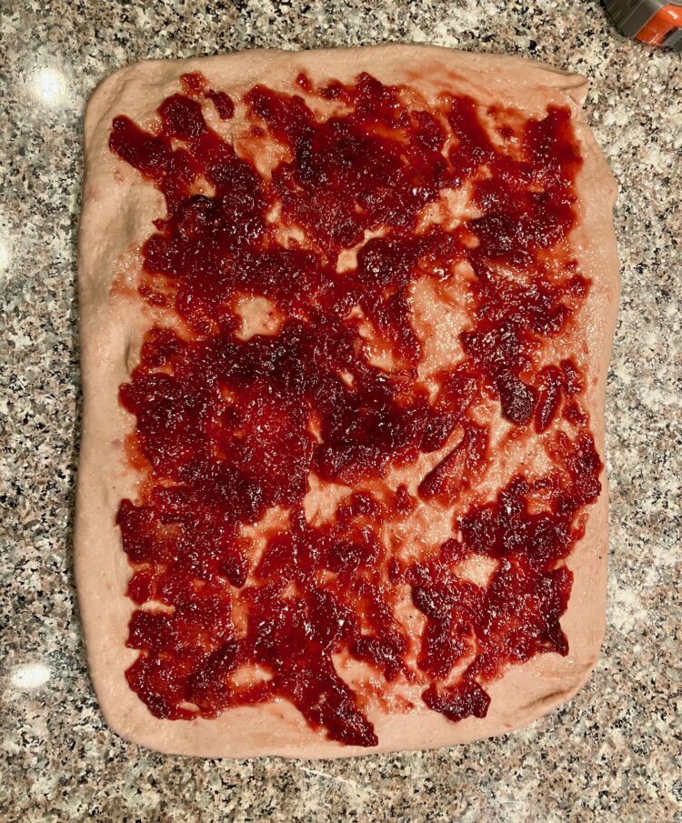 a rectangle of dough with strawberry jam spread on top